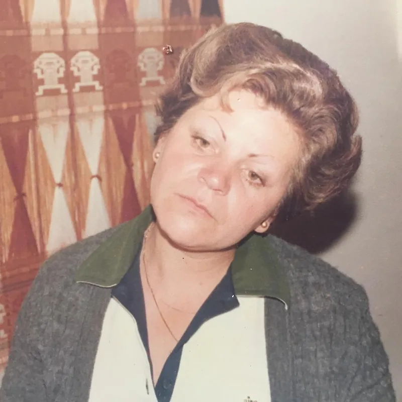 Clarita in 1980, short hair, grey cardigan with a green collar