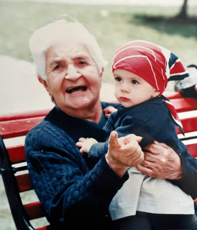 Elisa, white-haired and laughing, with baby Juliana Sofía in her arms