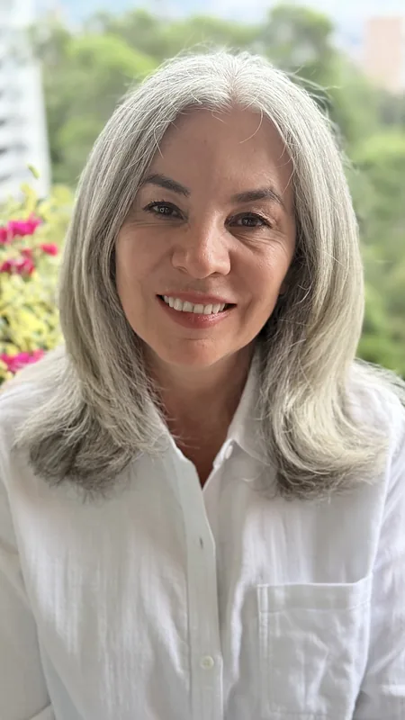 Dr Maritza Flórez, silver hair, white shirt, red flowers